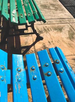 Close-up of blue and green painted wooden benches in a public park area