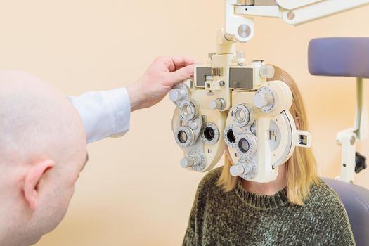 A male ophthalmologist checks a girl's eyesight using a phoropter. Vision treatment.