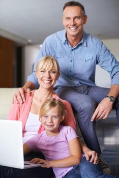 A family of three using a laptop in the lounge.