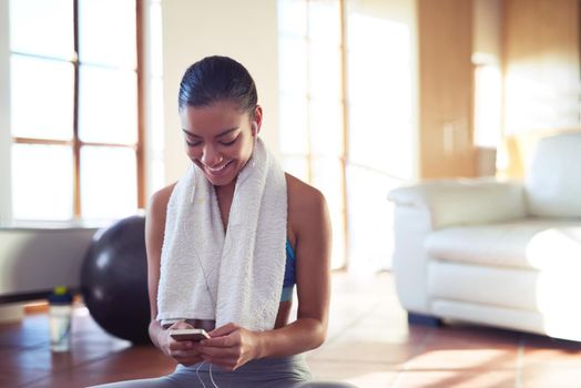 Cropped shot of a young woman checking her playlist while exercising at home.