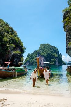 Koh Lao Lading near Koh Hong Krabi Thailand, beautiful beach with longtail boats, a couple of European men, and an Asian woman on the beach.