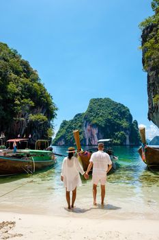 Koh Lao Lading near Koh Hong Krabi Thailand, beautiful beach with longtail boats, a couple of European men, and an Asian woman on the beach.