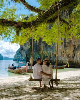 Koh Lao Lading near Koh Hong Krabi Thailand, beautiful beach with longtail boats, a couple of European men, and an Asian woman on the beach.