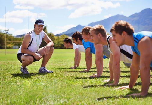 Young sportsmen training outdoors with a coach.