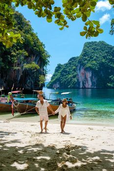 Koh Lao Lading near Koh Hong Krabi Thailand, beautiful beach with longtail boats, a couple of European men, and an Asian woman on the beach.