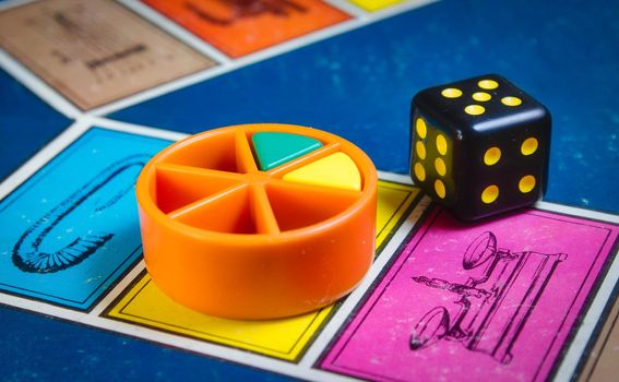 London, UK - 07 April 2019: Close-up of classic board game Trivial Pursuit with black die and colored plastic pieces of different colors