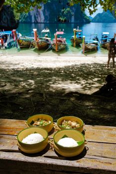 Koh Lao Lading near Koh Hong Krabi Thailand, beautiful beach with longtail boats, a couple of European men, and an Asian woman on the beach.