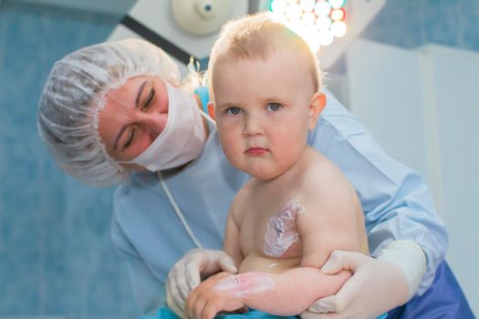 A nurse treats a sick child. Doctor and baby. Little patient with a burn and doctor