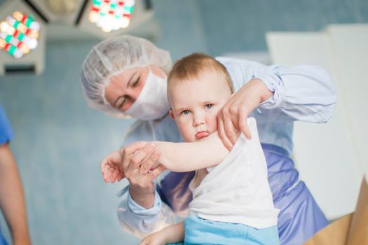 A nurse bandages a sick child. The doctor treats the baby. Little patient and doctor