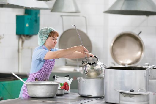 Cook with large pans and a ladle. Kitchen worker with a ladle. Worker dining.