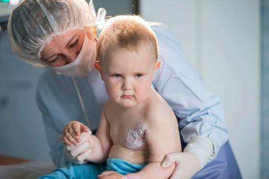 A little boy nurse treats a burn. A child in the hospital is injured. The doctor treats the baby. Little hospital patient.