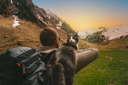 Man walking outdoors in mountains with his cat friend on the shoulder. Scene in nature at sunset. Man spending time with his pet. Best life moments . High quality photo