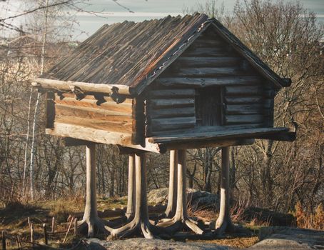 A traditional wooden log cabin on stilts in the forest