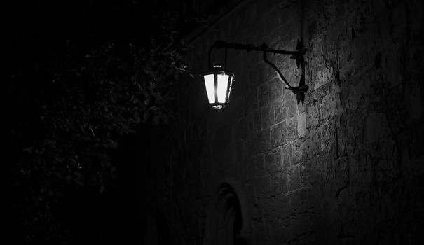 Spooky black and white alley with a lit street lamp