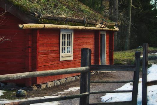 Old vintage wood cabin in the forest painted red
