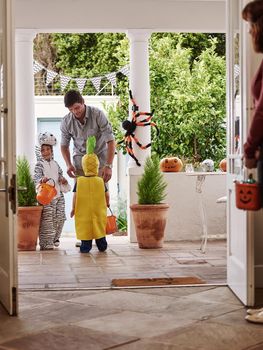 Full length shot of two adorable little boys celebrating halloween with their parents at home.
