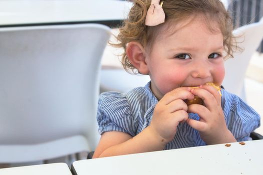 Cheeky little girl eating food looking at the camera smiling