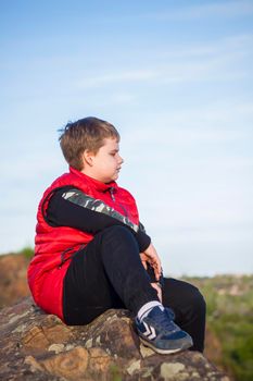 A child sits on top of a cliff and watches what is happening below. panoramic view from the top of a rocky mountain. Russia, Rostov region, skelevataya skala, the 7th wonder of the Don world. Landscape