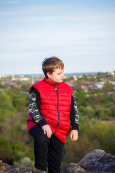 A child stands on top of a cliff and watches what is happening below. panoramic view from the top of a rocky mountain. Russia, Rostov region, skelevataya skala, the 7th wonder of the Don world. Landscape