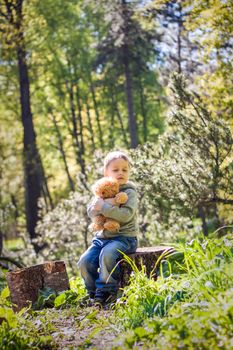 A cute boy is playing with a bear cub in the forest. The sun's rays envelop the space of the clearing with a stump. A magical story of interactions for the book. Space for copying. Selective focus.