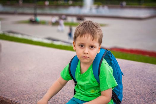 Portrait of a child, a boy against the backdrop of urban landscapes of skyscrapers and high-rise buildings in the open air. Children, Travel. Lifestyle in the city. Center, streets. Summer, a walk.