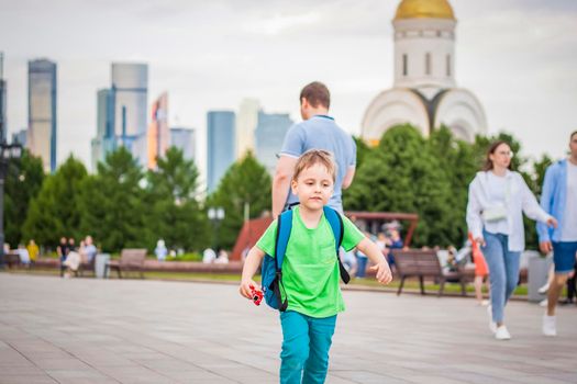 Portrait of a child, a boy against the backdrop of urban landscapes of skyscrapers and high-rise buildings in the open air. Children, Travel. Lifestyle in the city. Center, streets. Summer, a walk.