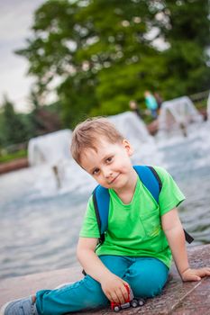 Portrait of a child, a boy against the backdrop of urban landscapes of skyscrapers and high-rise buildings in the open air. Children, Travel. Lifestyle in the city. Center, streets. Summer, a walk.