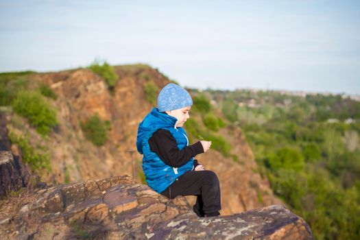 A child sits on top of a cliff and watches what is happening below. panoramic view from the top of a rocky mountain. Russia, Rostov region, skelevataya skala, the 7th wonder of the Don world. Landscape