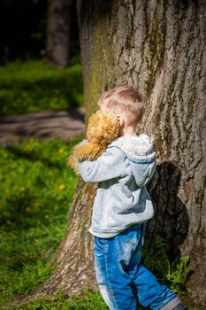 A cute boy is playing with a bear cub in the forest. The sun's rays envelop the space. A magical story of interactions for the book. Space for copying. Selective focus.