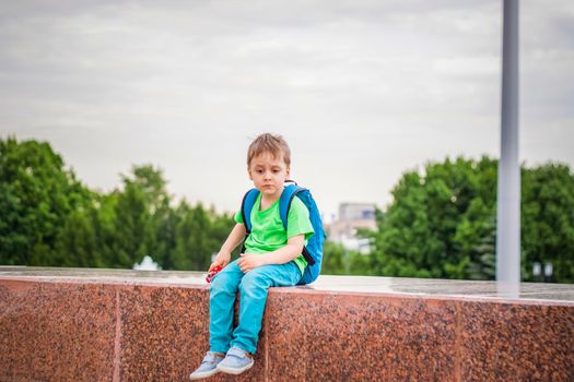 Portrait of a child, a boy against the backdrop of urban landscapes of skyscrapers and high-rise buildings in the open air. Children, Travel. Lifestyle in the city. Center, streets. Summer, a walk.