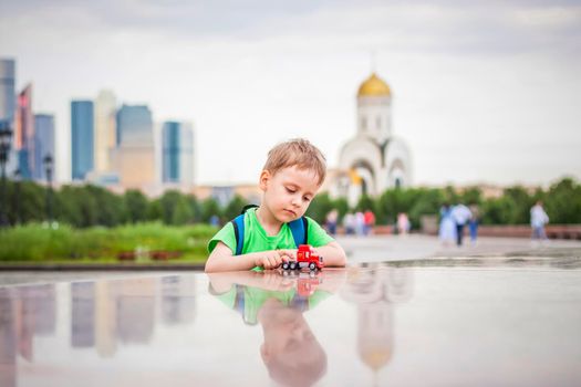 Portrait of a child, a boy against the backdrop of urban landscapes of skyscrapers and high-rise buildings in the open air. Children, Travel. Lifestyle in the city. Center, streets. Summer, a walk.