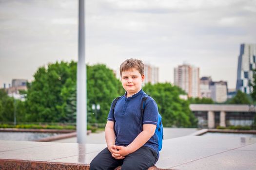 Portrait of a child, a boy against the backdrop of urban landscapes of skyscrapers and high-rise buildings in the open air. Children, Travel. Lifestyle in the city. Center, streets. Summer, a walk.