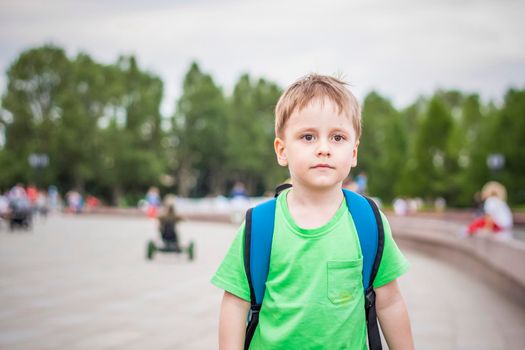 Portrait of a child, a boy against the backdrop of urban landscapes of skyscrapers and high-rise buildings in the open air. Children, Travel. Lifestyle in the city. Center, streets. Summer, a walk.