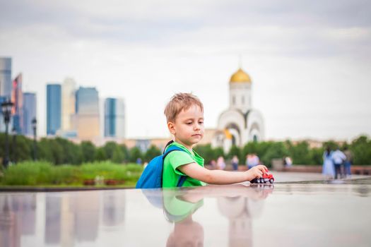 Portrait of a child, a boy against the backdrop of urban landscapes of skyscrapers and high-rise buildings in the open air. Children, Travel. Lifestyle in the city. Center, streets. Summer, a walk.