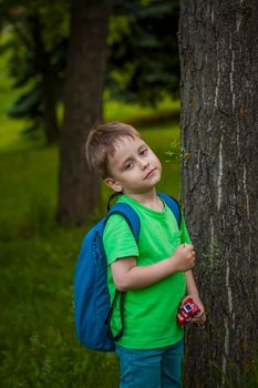 Portrait of a child, a boy against the background of plants in an open-air park. Children, Travel. Lifestyle in the city. Center, streets. Summer, a walk.