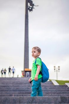 Portrait of a child, a boy against the backdrop of urban landscapes of skyscrapers and high-rise buildings in the open air. Children, Travel. Lifestyle in the city. Center, streets. Summer, a walk.