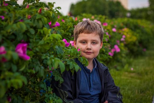 Portrait of a child, a boy against the background of plants in an open-air park. Children, Travel. Lifestyle in the city. Center, streets. Summer, a walk.