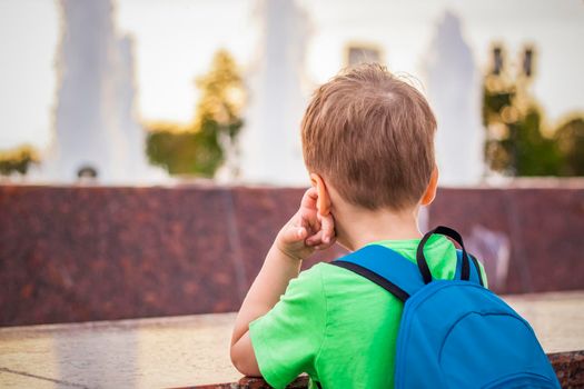 Portrait of a child, a boy against the backdrop of urban landscapes of skyscrapers and high-rise buildings in the open air. Children, Travel. Lifestyle in the city. Center, streets. Summer, a walk.