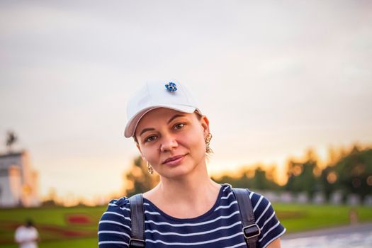 Portrait of a girl in a cap on the background of an open-air urban landscape. Travel. Lifestyle in the city. Center, streets. Summer, a walk.