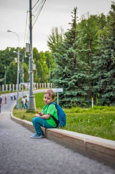 Portrait of a child, a boy against the backdrop of urban landscapes of skyscrapers and high-rise buildings in the open air. Children, Travel. Lifestyle in the city. Center, streets. Summer, a walk.