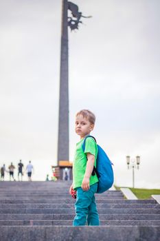 Portrait of a child, a boy against the backdrop of urban landscapes of skyscrapers and high-rise buildings in the open air. Children, Travel. Lifestyle in the city. Center, streets. Summer, a walk.