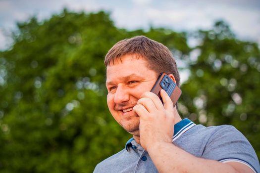 A man with joyful emotions on his face is talking on a mobile phone. Travel. Lifestyle in the city. Center, streets. Summer, a walk.