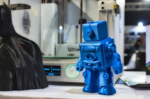 3D printed robot model next to a 3d printer at a technology and gadget fair