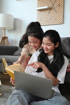 Two lovely young teenage girls doing homework together and helping each other.