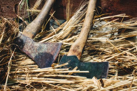 A pair of axes for chopping wood against straw background