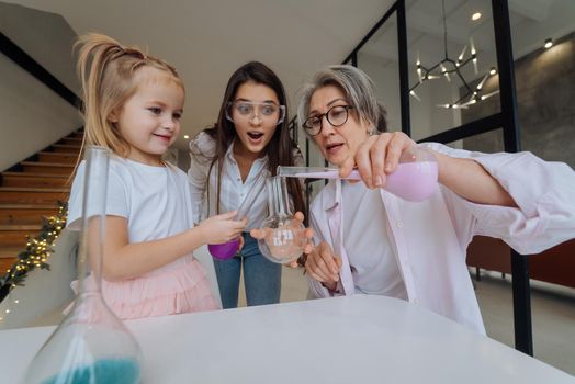 Family doing chemical experiment, mixing flasks indoors, close view.