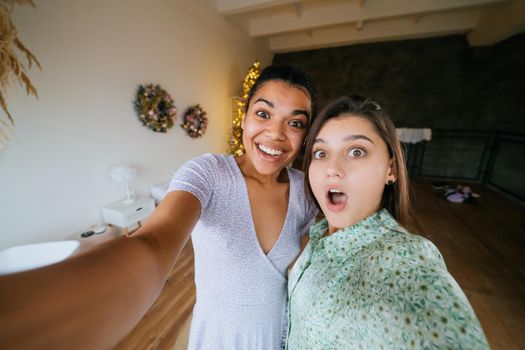 Two girls take selfies in the living room, look at the cameras and smile