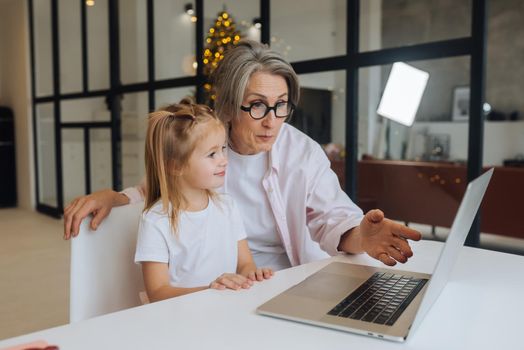 Child and granny looking at the camera with laptop at home