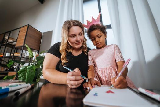 Mother and child daughter draws creatively at home at the table