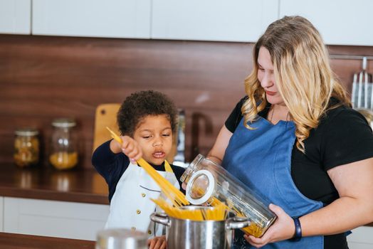 Happy family having fun in the kitchen. Mom teaches her little daughter to cook.